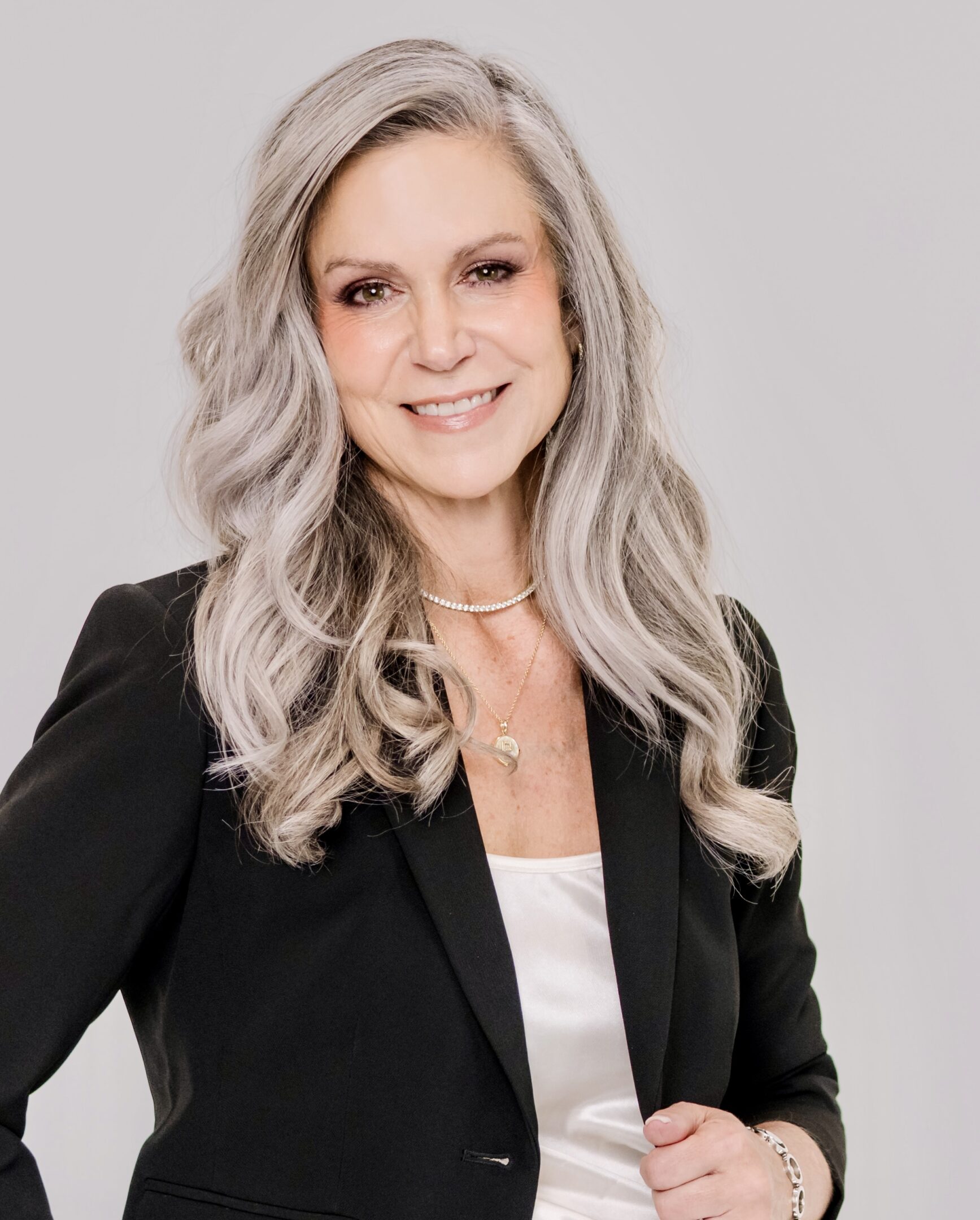 Professional woman with blonde hair in business attire smiling.