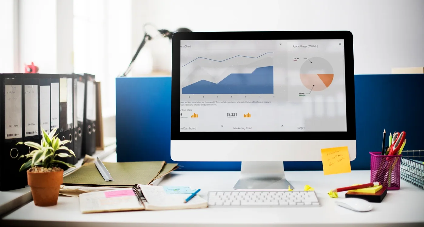 Workspace with a computer displaying graphs and charts.
