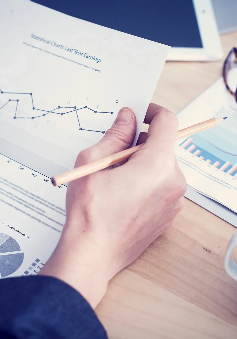 Person analyzing financial charts and graphs at a desk.