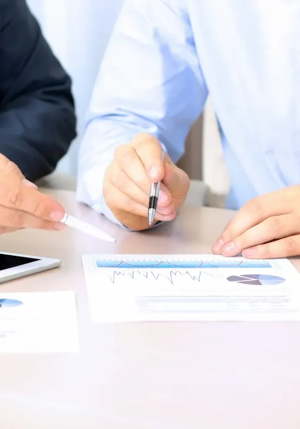 Two people reviewing documents and pointing at graphs.